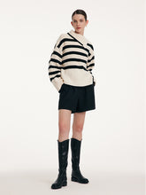 A lady wears a loose striped sweater.